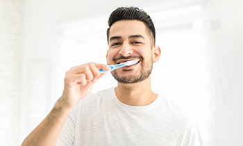 man brushing his teeth in bathroom