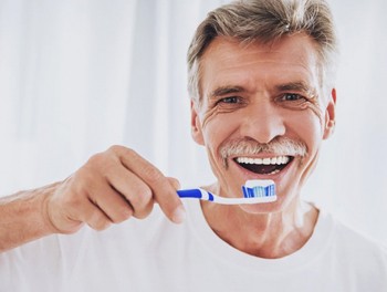 older man brushing his teeth to avoid needing gum disease treatment in Worthington 