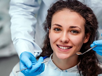young woman with curly hair smiling in dental chair