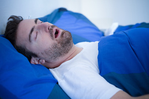 Bearded man with sleep apnea snoring in bed